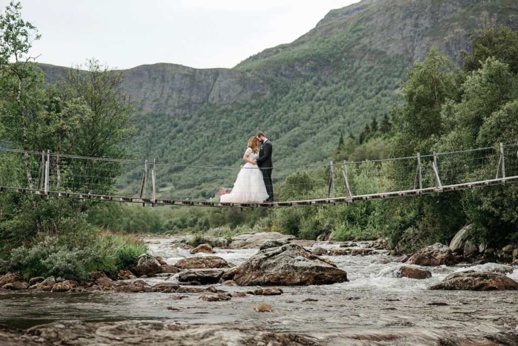 Boda en la montaña. Pareja de novios en un puente entre montañas verdes.