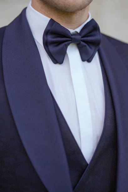 nOVIO CON TRAJE COLOR AZUL MARINO CON DETALLE DE SOLAPA EN TONO AZUL MÁS CLARO A JUEGO CON PAJARITA GRANDE DE MISMO COLOR