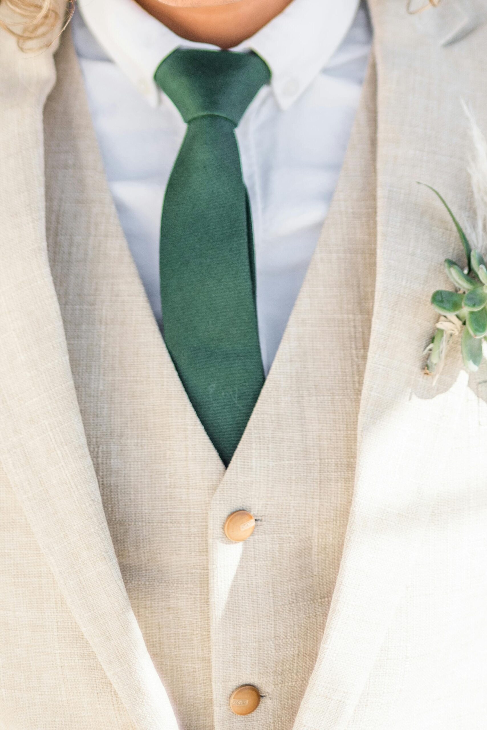 traje de novio color beige con corbata color verde con nudo sencillo.