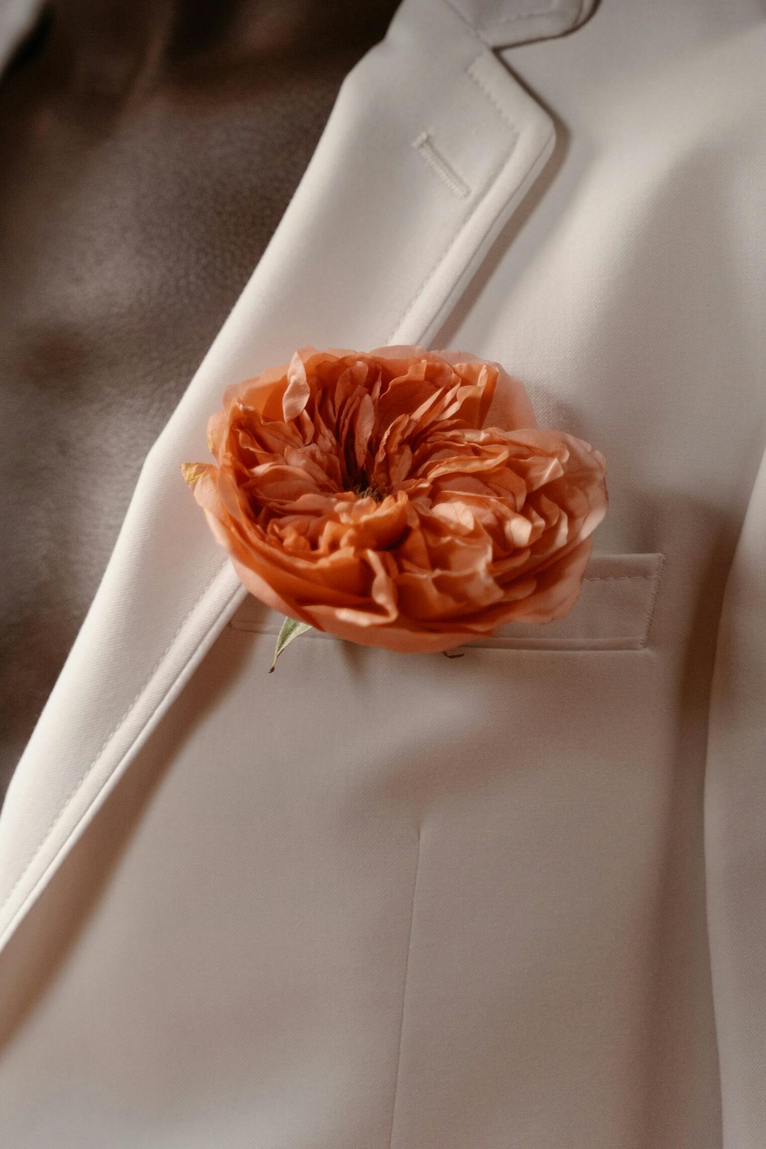 Traje novio color beige con detalle en el bolsillo de peonía naranja