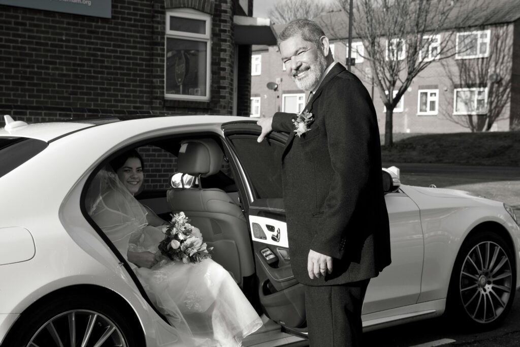 entrada novia en coche con padrino a boda por la iglesia