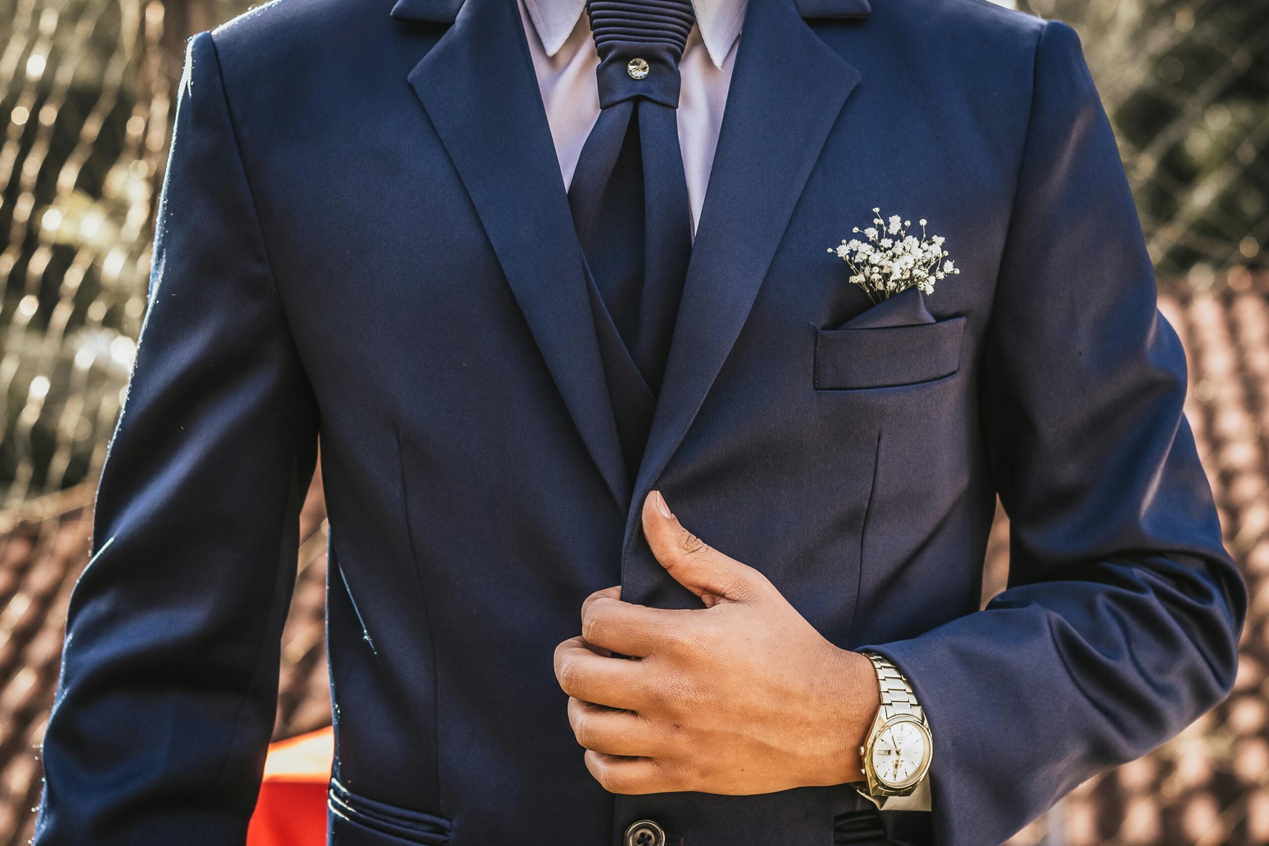 traje de novio azul marino con corbata a juego y detalle de joya