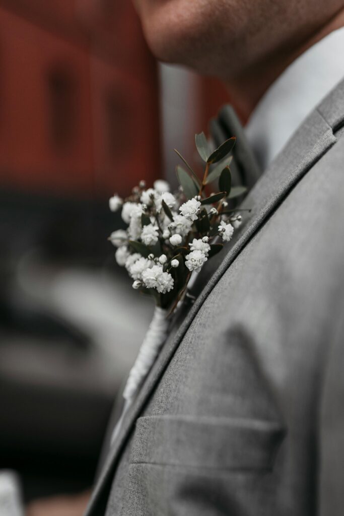 Boutonniere de paniculata blanca sobre traje de novio color gris